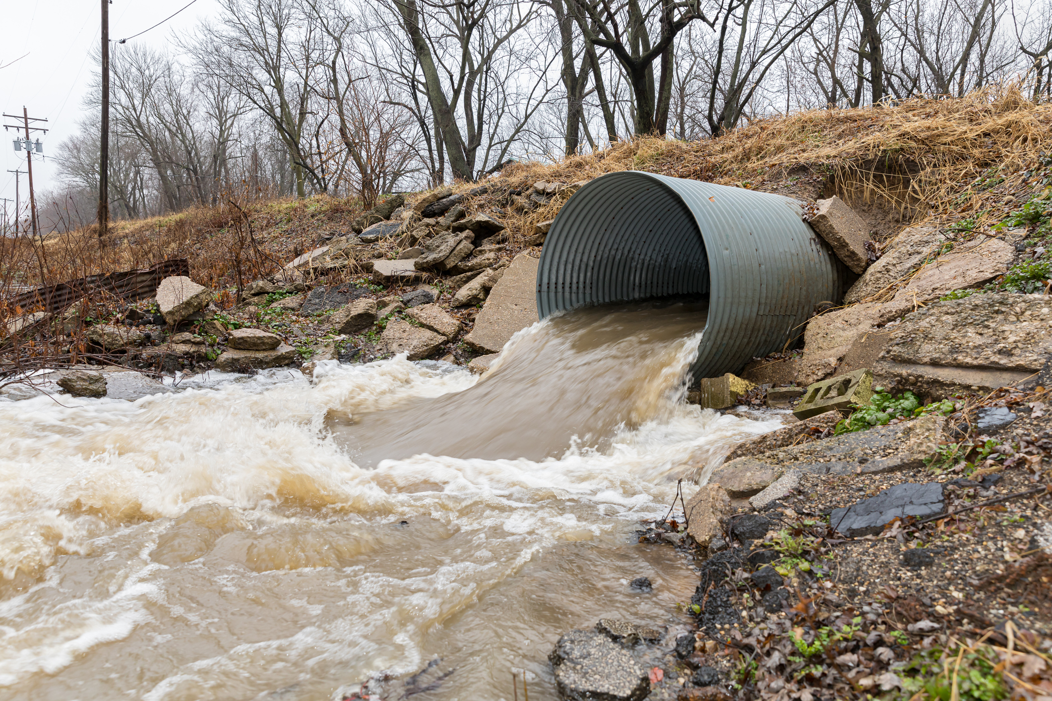 Water gushes out of a large drainage pipe during a 100-year storm event
