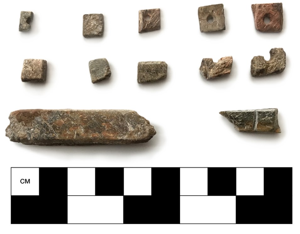 A flat array of 12 soapstone beads next to a measuring tool. An article in Cowboy Ecologist: Essays in Honor of Robert L. Bettinger argues that these beads were uses as micro-currency by the Foothill Yokuts.