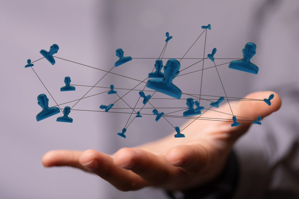 A hand holds a network of interconnected blue human icons linked by lines, visually representing communication and collaboration through on-call contract management structures.