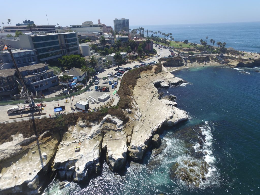 Coastal infrastructure and roadway above an eroding California bluff, illustrating emergency coastal protection, storm preparedness, infrastructure resilience, and environmental permitting considerations.